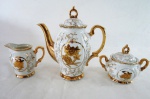 Um (1) bule para café, uma cremeira e um açucareiro em porcelana vitrificada, decoração floral em dourado. Med: bule de café 20 cm alt