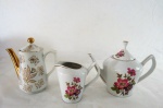 Um (1) bule chá, uma cremeira e um bule de café em porcelana vitrificada, decoração floral . Med. 18 cm alt.
