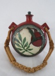 Antigo cantil em cerâmica vitrificada na cor marrom, decorada com folhagem  em verde e marfim, alça em sisal e bambu  marcada Aguero Rio 84. Med: 24 x 22 x 7 cm.