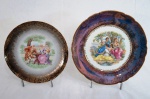 Lote constando de dois pratos decorativos sendo prato em porcelana decorado com figura de Ninfas ao centro, borda em azul com detalhes à folha de ouro e prato em porcelana decorado com Cena Galante ao centro, e borda em preto degradee com ricos detalhes floral e friso à folha de ouro. Med. 25 cm e 21 cm de diâmetro.