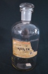 Um (01) frasco de farmácia em vidro branco transparente, rótulo antigo com inscrição: " H2 SO , marcado Industria Brasileira PYREX. Med. 23 cm alt x 10 cm diâmetro.