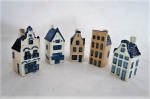 Cinco (05) casinhas de coleção em porcelana holandesa KLM. Padrão azul e branco. Med. maior 10 cm de alt. Menores 9 cm de alt. Duas das casas com bicados no gargalo ( chaminé).