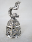 Sineta em metal espessurado a prata decorado com figuras Mitológicas  e pega no formato de peixe.Med.: 10 cm. alt.