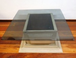 Imponente mesa de centro expositora de madeira patinada no tom marfim, no formato quadrada, tampo móvel com vidro fumê temperado, laterais com acabamento almofadados. Med. 80 x 70 cm.
