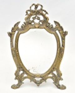 Espelho para apoio de mesa,  moldura de bronze e fundido no padrão Napoleão III, com pés de leão, folhas de acanto e terminam em laços, medindo 36 x 23,5 cm. Espelho bizotado com manchas do tempo.