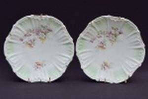 Par de pratos de porcelana alemã,  decorativos de borda recortada e decorado com pequenas flores . Diâmetro 20 cm.