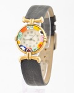 Relógio quartzo com cercadura no mostrador imitando milifiori veneziano. Caixa dourada, alças únicas de cada lado. Pulseira de couro. Sem funcionar.