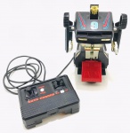 Anos 80 - Carro de controle remoto com fio, funcionando perfeitamente, carrinho vira robô. Obs: falta a tampinha do controle remoto onde leva a pilha.