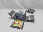 Caneca em porcelana com caixa em tecido, acompanha porta copo e bloco de anotações. Medindo a caixa 14cm x 14cm x 13cm de altura.