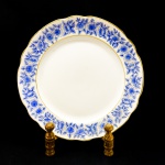 PORCELANA - Prato para bolo em porcelana, pintada a mão com decoração floral azul e acabamentos em dourado. Dia. 30 cm.