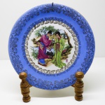 PORCELANA - Prato decorativo em porcelana, pintada a mão com cena oriental, faixa azul e ricos detalhes dourados. Dia. 25 cm.