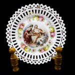 PORCELANA - Prato decorativo em porcelana com borda vazada e ao centro decorado com Ninfas. Dia. 21 cm.