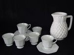 Sete peças: a) Jarra para refrescos em cerâmica vitrificada branca moldada na forma de abacaxi. Alt. 21cm. b) SCHMIDT - Seis xícaras com pires para chá em porcelana branca, pires oitavados. 10 x 15cm.