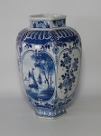 Vaso sextavado em porcelana holandesa, fundo branco decorado com moinhos, barcos e flores em azul. marcado no fundo Delft. Fio de cabelo na borda. Alt. 24cm.