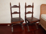 Par de cadeiras em madeira brasileira, pernas em X, barras laterais do encosto torneados terminando em bilros, assento de madeira. Alt. total 110cm.