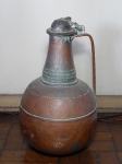 jarrão em cobre bojo liso, pescoço moldado com faixas, alça com corrente prendendo a tampa. Alt. 47cm.