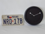 Duas peças: a) Placa em metal do estado do Texas, Estados Unidos. Numeração NRD-17B, "The Lone Star State". 31 x 16cm. b) Relógio de parede em plástico rígido, funcionamento a pilha, estilo contemporâneo. Diâm. 25cm.