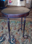 Mesa auxiliar oval, madeira nobre, pernas retilíneas com resquícios de douração, tampo em placagem. 77 x 73 x 50cm.