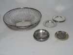 Doze (12) peças diversas em metal prateado: 9 porta-copos Mappin & Webb (diâm. 11,5cm), porta-garrafas (diâm. 10cm), fruteira gradeada (7x30cm) e tampa de pote.
