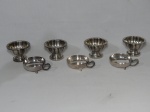 Sete  tacinhas para sorvete em metal prateado: a) Quatro com pé, modelo floral. Alt. 7cm. b) Três com alça e pés em volutas, bojo liso. Alt. 4cm.