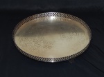 Bandeja em metal espessurado a prata, três pés, gradil coronado vazado, interior cinzelado com volutas e acantos. Diâm. 41cm.