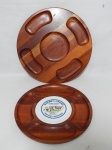 Duas tábuas para frios redondas em madeira nobre, uma com placa de cerâmica representando marca de queijo. Apresentam leves desgastes. Diam. 40cm e 38cm.