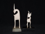 Duas esculturas em marfim representando cervos. Uma com base em resina e outra em granito. Um chifre quebrado. Alts. 16cm e 21 cm.