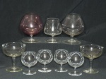 Nove taças em vidro diverso, sendo 7 para conhaque (um róseo) e 2 para champagne. Alt. Maior 12cm. Alt. menor 8cm.