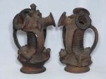 Par de jarros em barro cozido, estilo pré-colombiano, moldados com figuras animais e humanas. Apresenta lascados e bicados. Alt. 28cm.