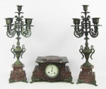 Terno em bronze e mármore rajado possivelmente europeu, composto de par de candelabros para 5 velas e caixa para relógio, tendo este mostrador em porcelana. No estado. Alt. candelabro 50,5 cm e Med. caixa 15,5x29x17 cm.