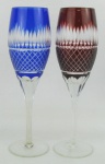 Par de taças de coleção, em cristal, sendo uma na tonalidade translucida e azul e a outra translucida e rubi. Lapidações dedão, sulcos bisotados e tijolinho. Alt. 22 cm.
