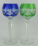 Par de taças de coleção em cristal europeu, sendo uma na tonalidade translucida e verde e a outra translucida e azul. Lapidações dedão e estrelas. Hastes sextavadas. Alt. 21 cm.