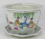 Belo cachepot com presentoir, sesctavado em porcelana chinesa, decorado com pintura policromada em cada face, com cena de gueixa na paisagem, tocando cada uma um instrumento diferente. Med. cachepot 17,5x26 cm.