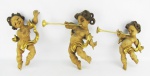 Três antigas e belas esculturas em madeira patinada com detalhes em dourado, representando "Puttinos", estando dois tocando trombeta. Alt. 30(2) e 25 cm.