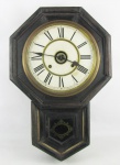 Relógio de parede americano, estilo gravatinha, com marca da manufatura Ansônia. Caixa em madeira entalhada e portas com vidro. Mostrador em números romanos. Marcas de uso e maquina necessita regulagem. Med. 55,5x37x12cm.