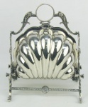 Biscoiteira em metal inglês, espessurado a prata, na forma de concha com abertura ao meio, tendo em seu interior divisórias com detalhes vazados. Guarnições com trabalhos de folhagens, flores, perolados e volutas. Apresenta localizado Made in England na borda. Med. aberta 26x33x22 cm.