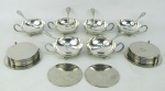 a) Quatorze descansos para copos em metal espessurado a prata, decorados com trabalhos de folhagens. Diam. 9,5cm. b) Seis taças para sorvete com colheres, em metal espessurado a prata, com marca da manufatura Eberle, decorados com folhagens e frutos em relevo. Colheres com pequenas marcas de uso.  Med. taças 4,5x12x9cm. Comp. colheres 14,5cm.