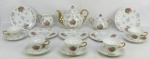 Aparelho para chá em porcelana, decorado com cena de casal de nobres em policromia e detalhes em dourado, composto de bule, leiteira, açucareiro, 5 pratos para sobremesa e 5 xicaras. Parte interna da tampa do bule e borda de uma xicara com bicado. Total 13 peças. Alt. bule 15,5cm.