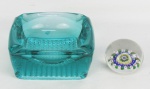 Duas peças, sendo cinzeiro em vidro no tom verde e pisa papeis em murano com decoração millefiori em policromia. Pisa papeis com marcas de uso e bicado na base. Med. cinzeiro 6x14,5x14,5cm.