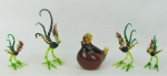 a) Quatro esculturas miniatura em murano policromado, representando "Galos". O maior com parte de um dedo quebrado. Alt. maior e menor 12,5 e 7cm. b) Escultura miniatura em murano no tom âmbar representando "Galinha no choco". Alt. 7,5cm.
