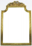 Espelho de parede com moldura em madeira entalhada e patinada de dourado, decorada com flores, folhas e laço de fita no ápice. Espelho com pequenas manchas causadas pelo tempo. Med. 104x72,5cm.