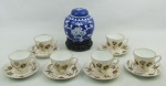 a) Seis xicaras para café em porcelana, decorados com flores, folhas e pássaros em tons de chocolate, com detalhes em dourado. Alt. xicara 5cm.b) Potiche em porcelana no tom azul, com flores e folhagens no tom leitoso. Acompanha peanha em madeira entalhada. Alt. total 14,5cm.