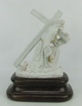 Escultura em pasta dura portuguesa com marca da manufatura Neca, representando "Cristo carregando a cruz". Detalhes em dourado. Base em madeira nobre entalhada. Alt. total 26cm.
