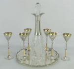 Conjunto de bandeja, licoreiro e 6 taças alemães, com marca da manufatura WMF, sendo a bandeja em metal espessurado a prata com trabalhos na borda, taças com parte da haste em marfim e interior em vermeil e licoreiro em metal e cristal lapidado. Diam. bandeja 23cm. Alt. licoreiro 28,5cm. e Alt. taças 13cm.