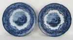 Par de pratos fundos em porcelana inglesa azul borrão com marca da manufatura Copeland nos versos. Aba decorada com folhagens, volutas e guirlandas de flores e ao centro paisagem com casas, lago e barco. Diam. 22,5cm.