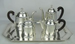 Serviço para chá e café em metal espessurado a prata, com marca da manufatura St. James na base, composto de 2 bules, leiteira, açucareiro e bandeja. Alças dos bules em madeira. Med. bandeja 53,5x36,5cm.