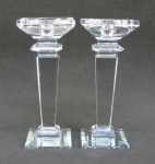 Par de castiçais em cristal translúcido, decorados com lapidações facetadas. Bases espelhadas. Alt. 21,5cm.