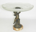 Porta cartões europeu, em bronze na forma de querubim, sobre coluna, sustentando prato em cristal com trabalhos em satiné e translúcido. Borda em ondulações. Base oitavada em mármore rajado, apresentando estes dois, pequenos bicados. Med. 20,5x22,5 cm.