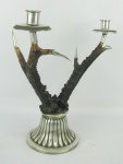 Castiçal para 2 velas com hastes em chifre e guarnições em prata com marca do teor 925 milésimos. Base trabalhada com gomos em relevo. Uma haste com colagem próximo a base. Alt. 29cm.