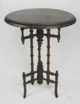 Mesa de apoio em madeira entalhada com tampo circular, se apoiando sobre três colunas torneadas com elos. Três pés curvos. Marcas de uso. Med. 81x59,5 cm.